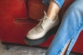 Close-up to urban sneakers on teen girl sitting on old leather armchait in retro and vintage style