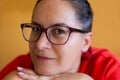 Close up of a 45 to 50 year old woman wearing glasses and dressed in red with a relaxed, smiling and self-confident expression. Royalty Free Stock Photo