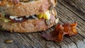 Close up of a toasted breakfast sandwich on pumpkin seed bread with a crispy slice of bacon in front.