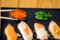 Close-Up of Tobiko Sushi Lifted with Chopsticks with other pieces as background