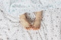 Close-up of toddler girl`s feet on the bed under the blanket. Light blue and beige tones Royalty Free Stock Photo