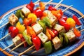 close-up of tofu skewers with mixed veggies on a blue ceramic dish