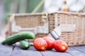 Close up of tomatoes and cucumbers over wooden table in front of an open picnic basket.