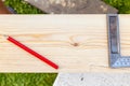 A close-up of tools for drawing markings on wood - a red graphic pencil and a metal ruler on a beam against the background of Royalty Free Stock Photo