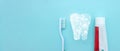 Close up of a toothbrush and toothpaste with thin linear Low poly tooth icon on blurred blue background. Means to care for the