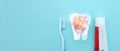 Close up of a toothbrush and toothpaste with thin linear Low poly tooth icon on blurred blue background. Oral Care Concept. Royalty Free Stock Photo