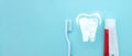 Close up of a toothbrush and toothpaste with thin linear Low poly tooth icon on blurred blue background. Oral Dentist stomatology