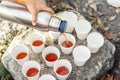 Close-up top above view woman hand hold steel thermos pouring hot tea many white paper cup group picnic mountain