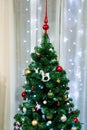 Close-up of the top of a Christmas tree decorated with toys and balls against the backdrop of a garland. Royalty Free Stock Photo