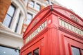 Close up of the top of a London telephone booth and a brick building behind it Royalty Free Stock Photo