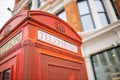 Close up of the top of a London telephone booth and a brick building behind it Royalty Free Stock Photo