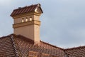 Close-up top of new big modern house with shingled red roof, high brick plastered chimney and snow protection fence against bright Royalty Free Stock Photo