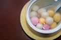 Close up top side view of red, orange and white tangyuan tang yuan, glutinous rice dumpling balls in white bowl.