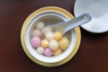 Close up top side view of red, orange and white tangyuan tang yuan, glutinous rice dumpling balls in white bowl.