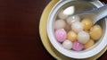 Close up top side view of red, orange and white tangyuan tang yuan, glutinous rice dumpling balls in white bowl.