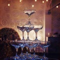 Close up of top tiers of champagne tower at the faint light of a banquet hall. Beautifull built-in set of coupe glasses