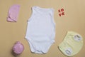 Close-up top view. Blank white bodysuit mockup, yellow newborn panties on beige background, with copy space - perfect baby clothes