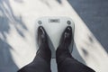 Close up and top view of business man feet on scales asking for help. Lose weight concept