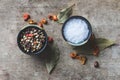 Close up and top view of chilly peppers, bay leaves, and coarse salt and allspice in ceramic containers on old rustic table Royalty Free Stock Photo