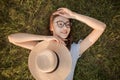 Close-up top view of a girl in the park lying on the green grass. Glasses and hat. Happy youth leisure and recreation Royalty Free Stock Photo