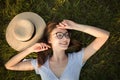 Close-up top view of a girl in the park lying on the green grass. Glasses and hat. Happy youth leisure and recreation Royalty Free Stock Photo