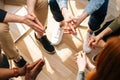 Close-up top view of group diverse multiethnic people sitting in circle with hands crossed hands together during