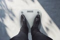 Close up and top view of guy in suit feet on scales asking for help. Lose weight concept