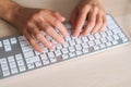 Close-up top view hands of unrecognizable business man using wireless computer keyboard sitting at light working desk in Royalty Free Stock Photo