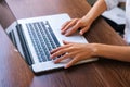 Close-up top view hands of unrecognizable young business woman working online, typing on laptop keyboard, sitting at