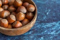 Close-up on top view of hazelnuts in wooden bowl on blue marble background Royalty Free Stock Photo