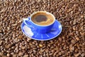 Close-up and top view of hot black coffee in blue coffee cup and roasted Thai coffee beans on wooden background. Royalty Free Stock Photo