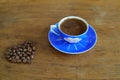 Close-up and top view of hot black coffee in blue coffee cup and roasted Thai coffee beans on wooden background. Royalty Free Stock Photo