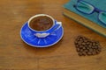 Close-up and top view of hot black coffee in blue coffee cup and roasted Thai coffee beans on wooden background. Royalty Free Stock Photo