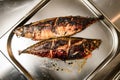 Close-up of top view of metal tray with grilled fish.