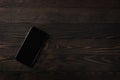 Close up top view of a modern smartphone on black wood table background Royalty Free Stock Photo
