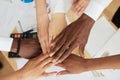 Close-up top view: multinational employees put their hands in a pile, showing support and unity, together towards a