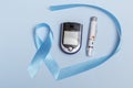Close-up top view of 14 November World Diabetes Day concept. Blue tape with blood drops and a glucometer on a blue background.