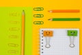 Close up top view photo of school supplies. Set of spiral notepad, clips and pencils on yellow and green background Royalty Free Stock Photo