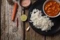 Close-up top view of plate with delicious chicken tikka masala curry and rice on rustic wooden table with spices background. Royalty Free Stock Photo