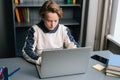 Close-up top view of pupil boy using typing laptop computer doing online lesson via Internet at desk near window. Royalty Free Stock Photo