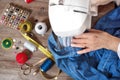 Close-up top view, of senior woman hands seamstress sewing jeans on electrical sewing machine.