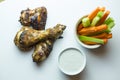 Close up top view shot of isolated grilled barbecue chicken wings and legs, a bowl of fresh orange carrots and juicy green celery Royalty Free Stock Photo