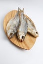 Close up top view shot of three Russian dried salted vobla Caspian Roach fish on a wooden plate on a white background