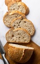 Close-up, top view slices of sourdough bread on a wooden board on a white marble background. Organic baked goods. Wheat Royalty Free Stock Photo