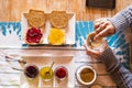 Close up top view of table with healthy food and adult woman doing breakfast - marmalades fruits and coffee time - coloured image