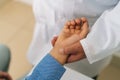 Close-up top view of unrecognizable male doctor examining wrist of suffering young man patient during checkup visit in