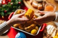 Close-up top view of unrecognizable young woman and man passing delicious boiled corn sitting at festive Christmas table Royalty Free Stock Photo