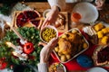 Close-up top view of unrecognizable young woman and man passing delicious food sitting at festive Christmas table during Royalty Free Stock Photo