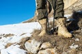 Close-up of a tourist`s foot in trekking boots with sticks for Nordic walking standing on a rock stone in the mountains Royalty Free Stock Photo