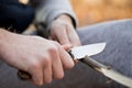 Close-up of the tourist`s hands, sharpening a stick with a knife. The concept of travel, extreme and survival Royalty Free Stock Photo